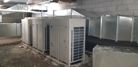 Outdoor condenser units mounted on a bracket against an exterior wall